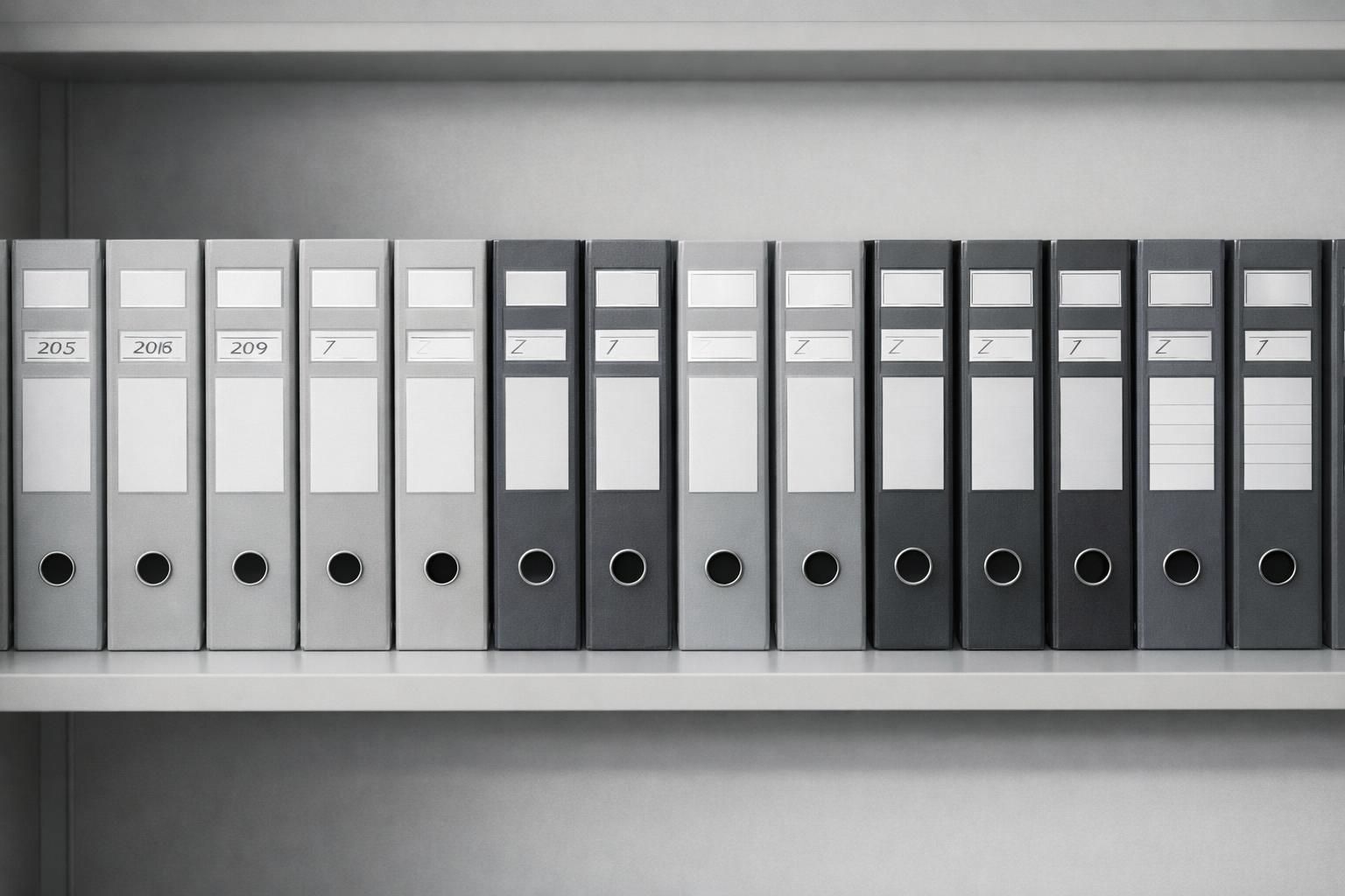 Boîtes d'archives et classeurs étiquetés par années alignés sur une étagère